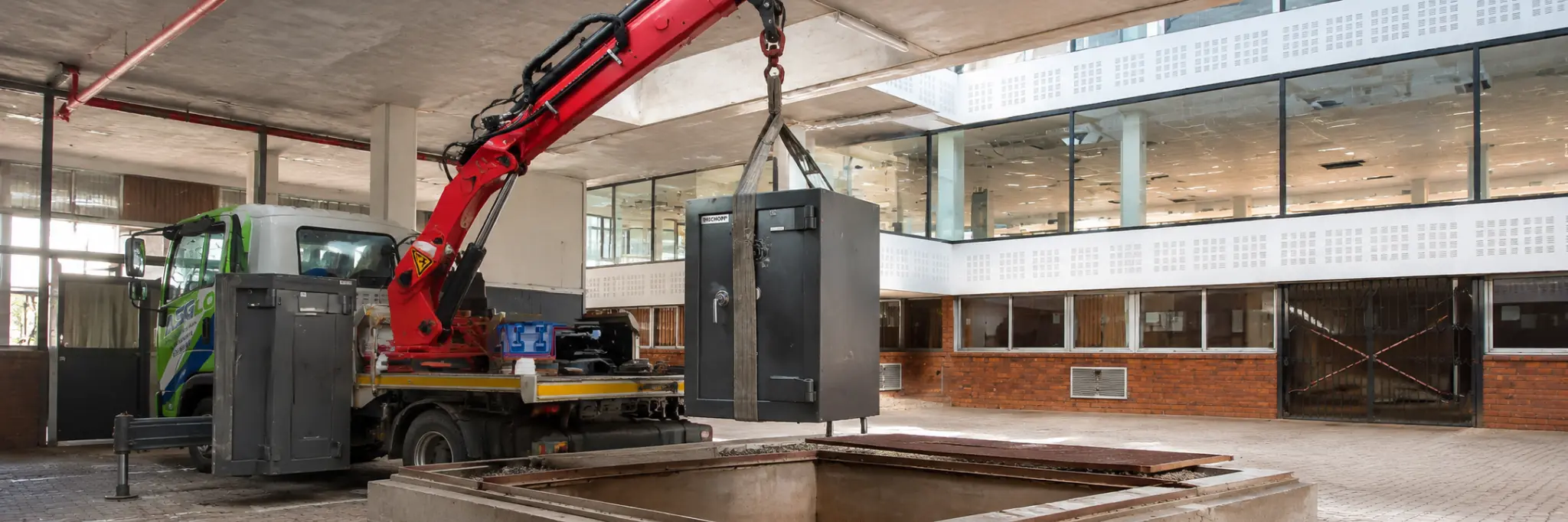 A heavy safe being lifted from a truck into a building